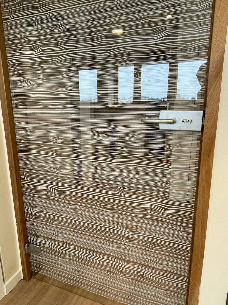 Design contemporain du film décoratif d'intimité installé sur la porte vitrée de bureaux dans l'Hérault