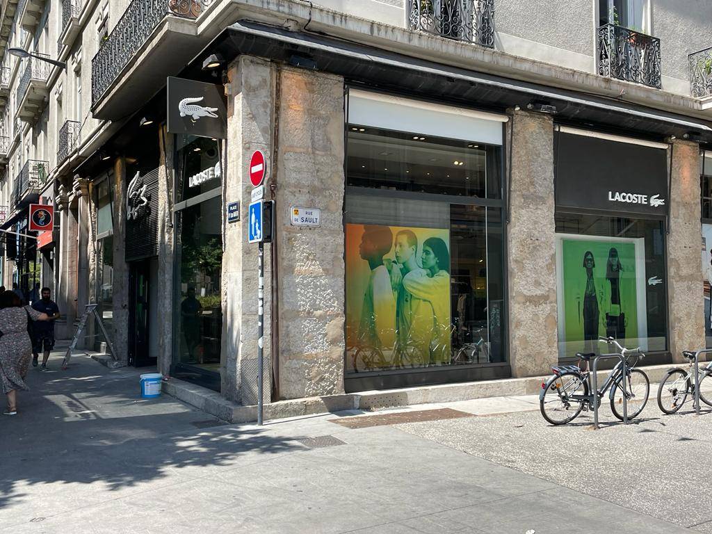Application d'un film solaire anti décoloration sur les vitrines du magasin LACOSTE de Grenoble